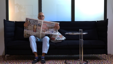 Jörg Pfannenberg auf dem Sofa mit einer Zeitung.